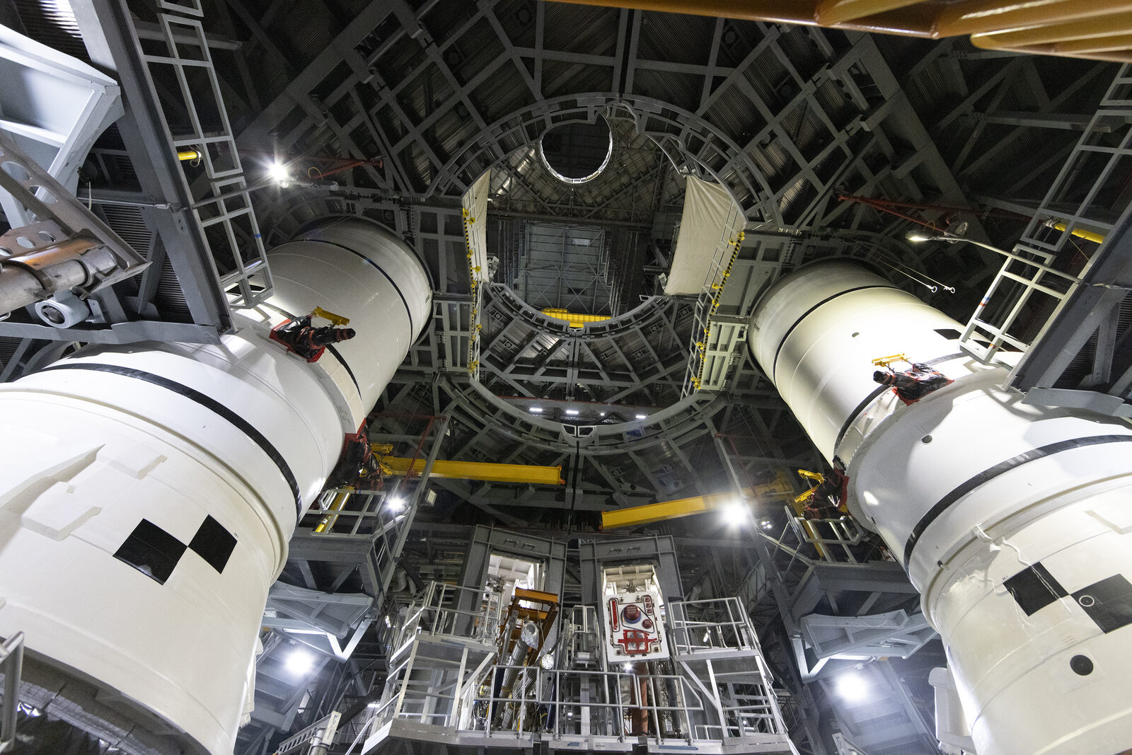 Engineers lower a segment of the Artemis II SLS solid rocket booster into place on the mobile launcher at Kennedy Space Center