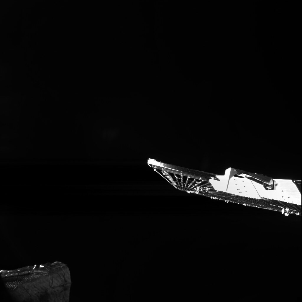 A sunlit solar wing and part of a spacecraft body, edge-on against deep black space