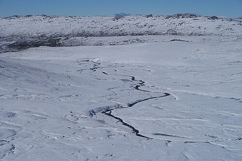 Snow-covered slopes and rocky ridgelines of the Main Range in Kosciuszko National Park under a blue sky