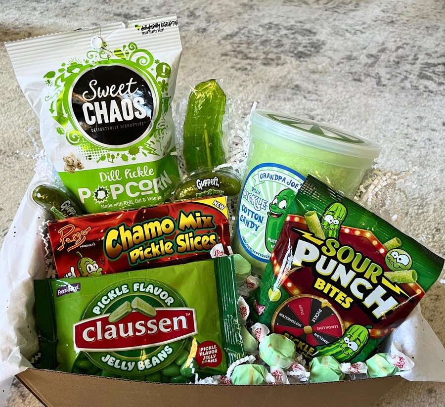 A gift box full of pickle-flavored snacks: dill pickle popcorn, pickle cotton candy, pickle jelly beans, pickle Sour Punch, and more