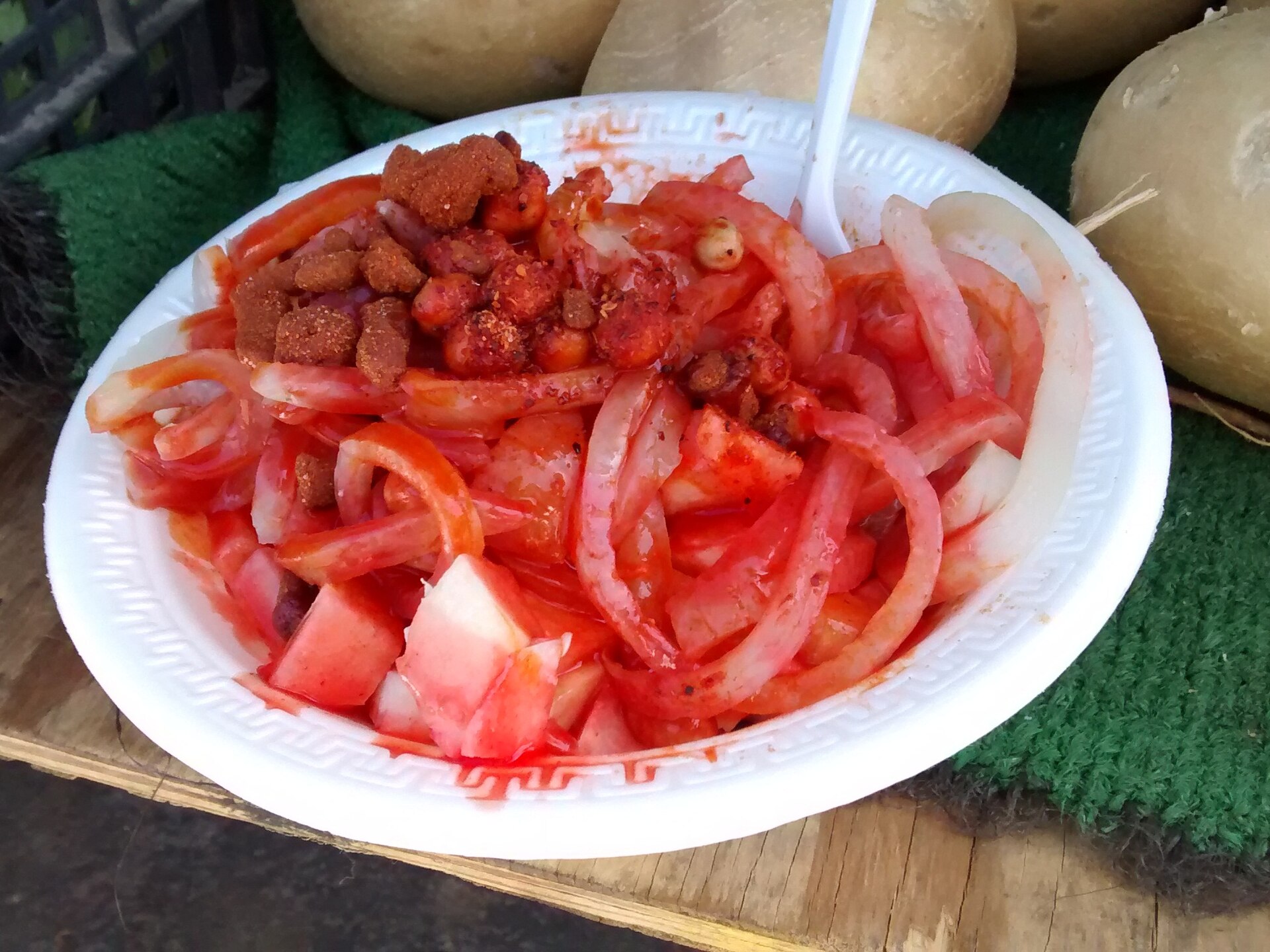 A bowl of tostilocos with jícama, cucumber, chamoy sauce and tamarind candy on top of tortilla chips