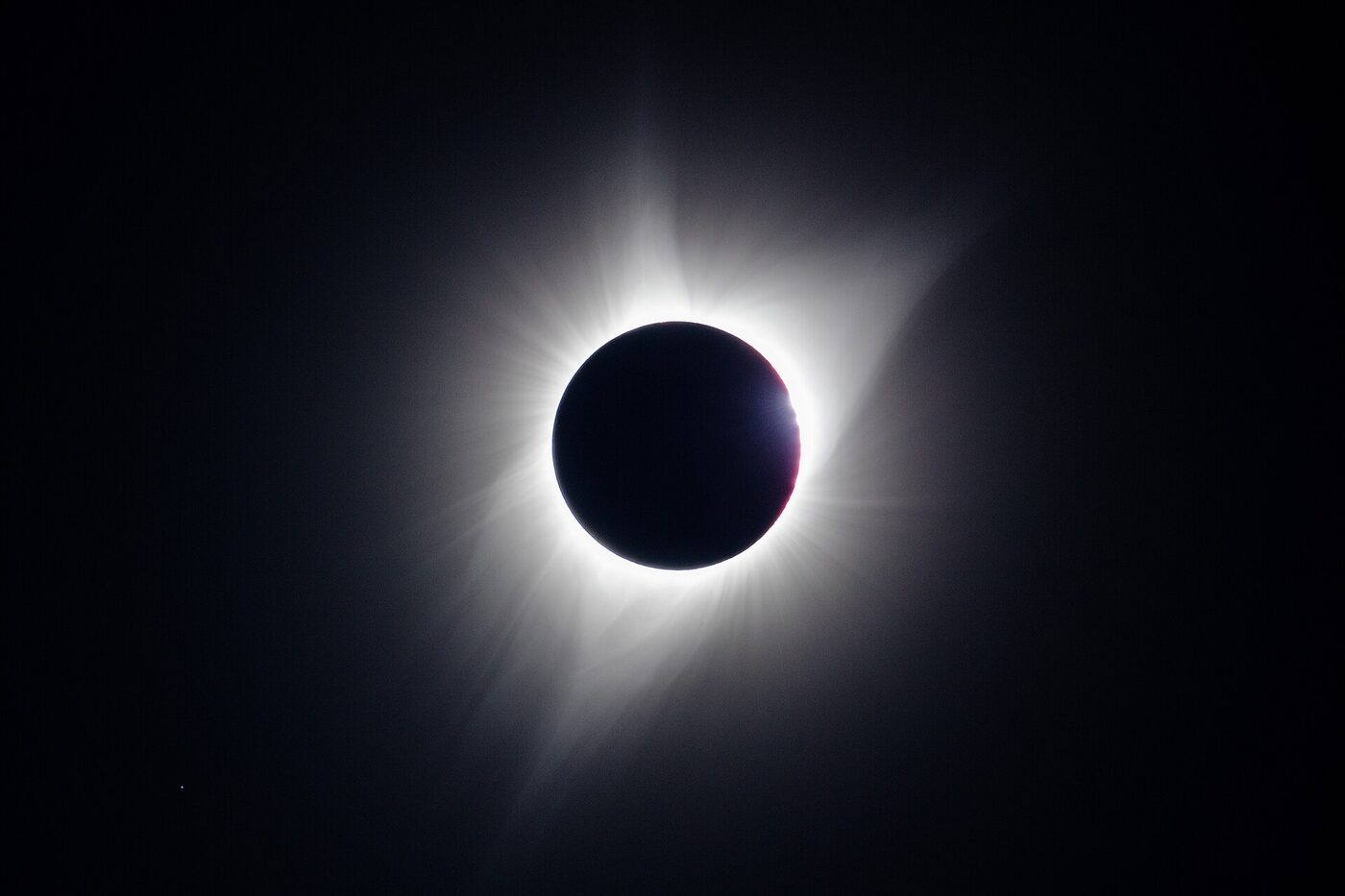 A black lunar disc surrounded by a bright white corona, with one small brilliant bead of sunlight glinting at the right-hand edge