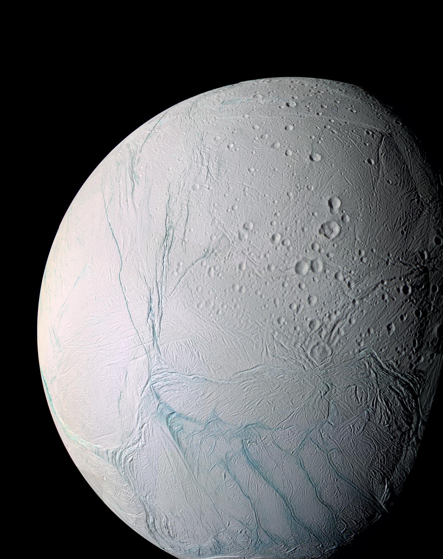 A high-resolution view of the fractured, grooved surface of Enceladus, deep parallel canyons and ridges carved into bright white ice