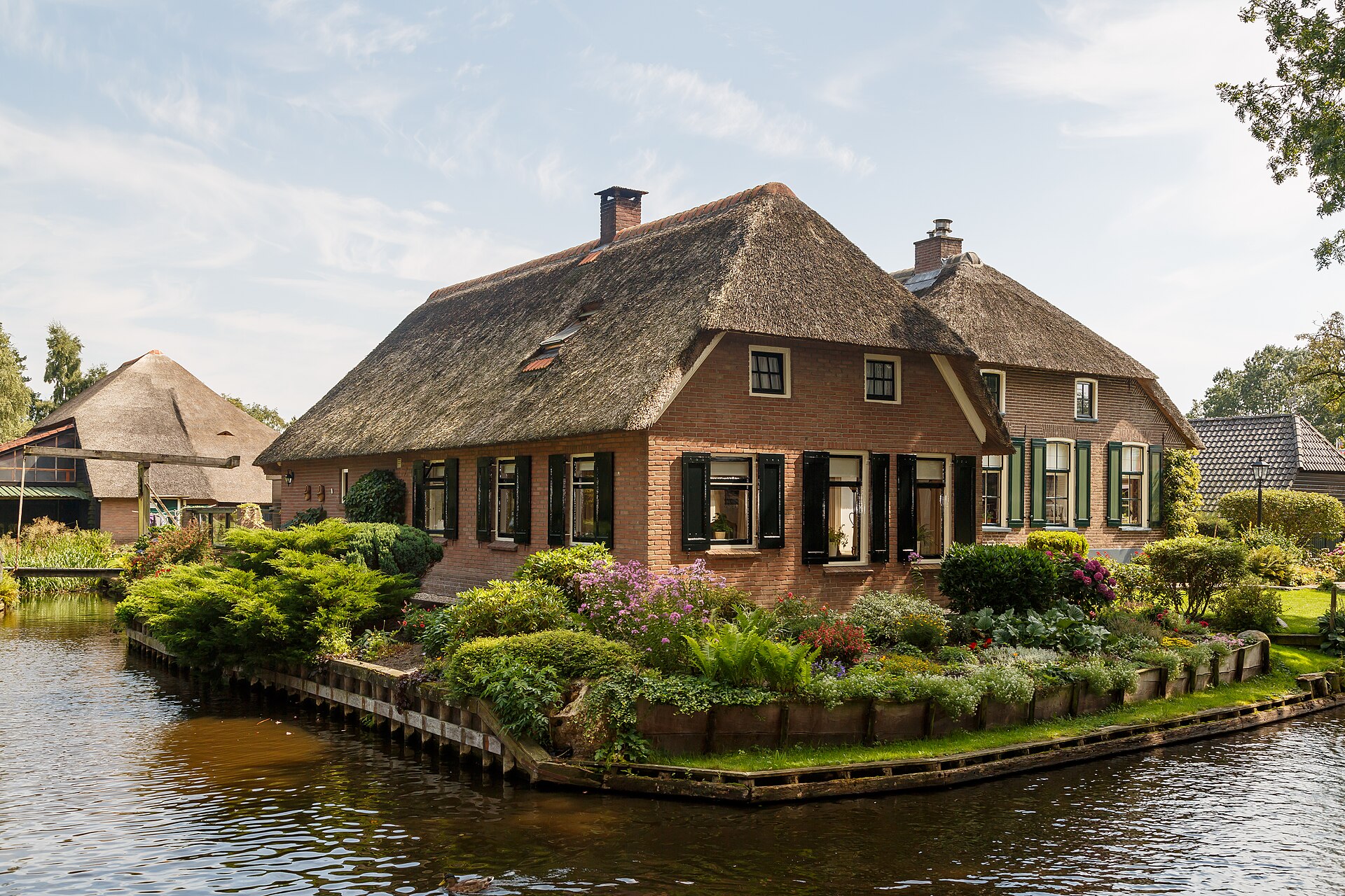 A thatched-roof cottage on a small island in Giethoorn, surrounded by garden and canal water