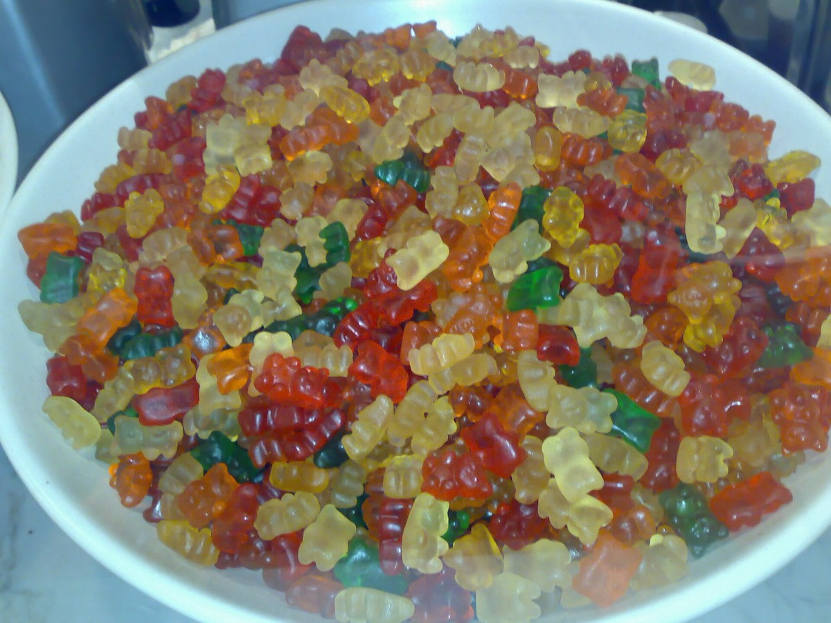 A large white bowl heaped with hundreds of gummy bears in many colors
