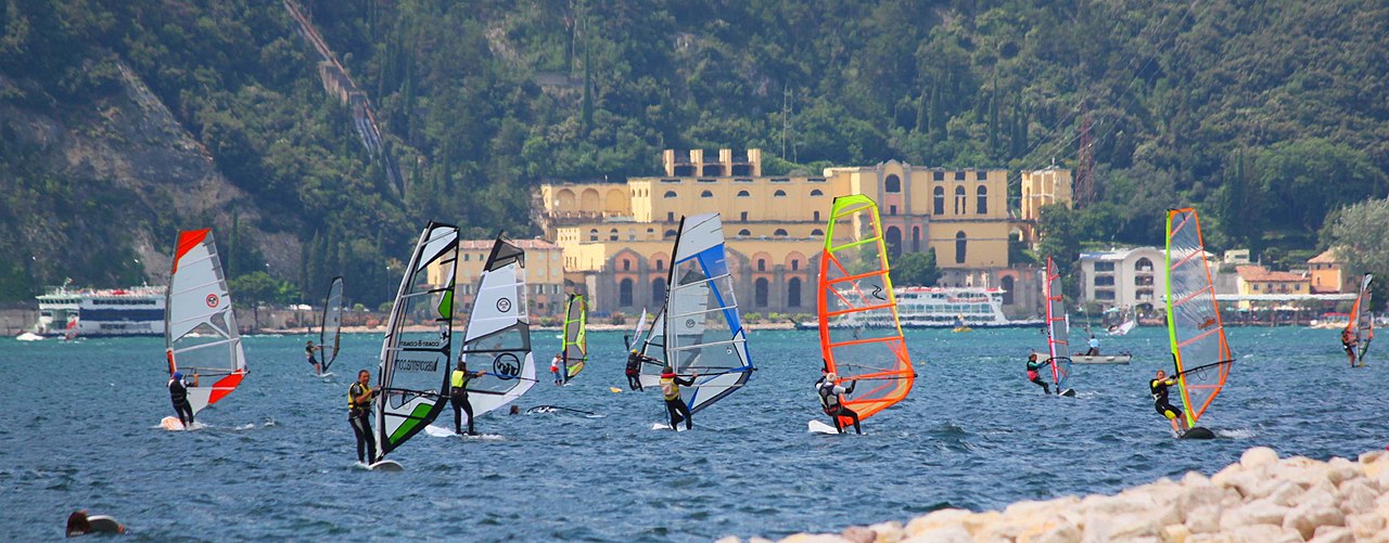 A windsurfer skimming across the choppy northern waters of Lake Garda below steep mountains