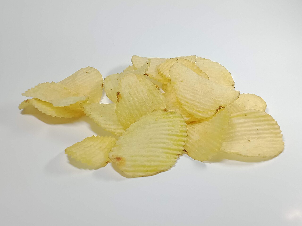 A pile of plain ridged wavy-cut potato chips on a white background