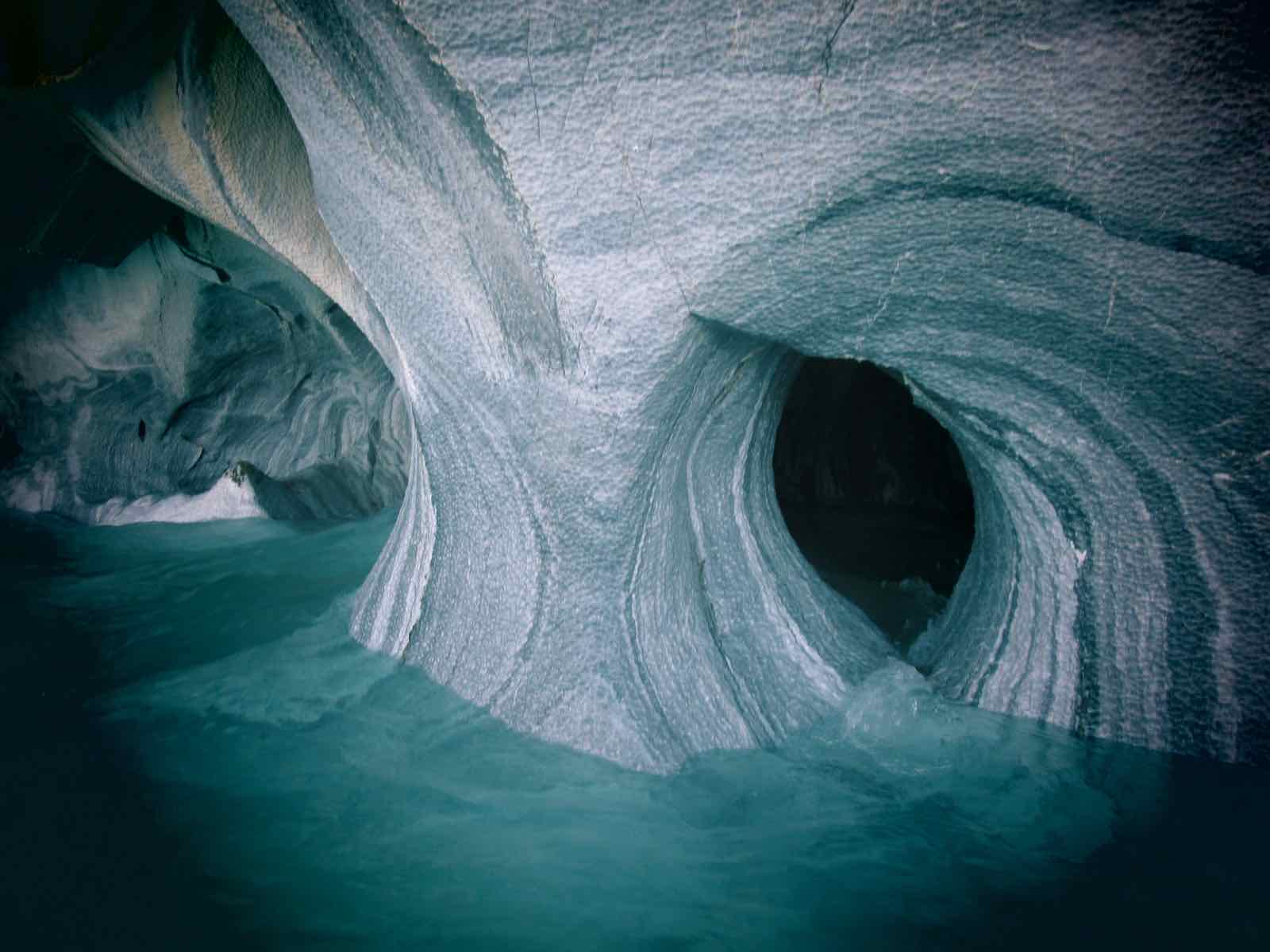 The interior of the Marble Cathedral, with rippled marble ceilings reflected in calm blue water