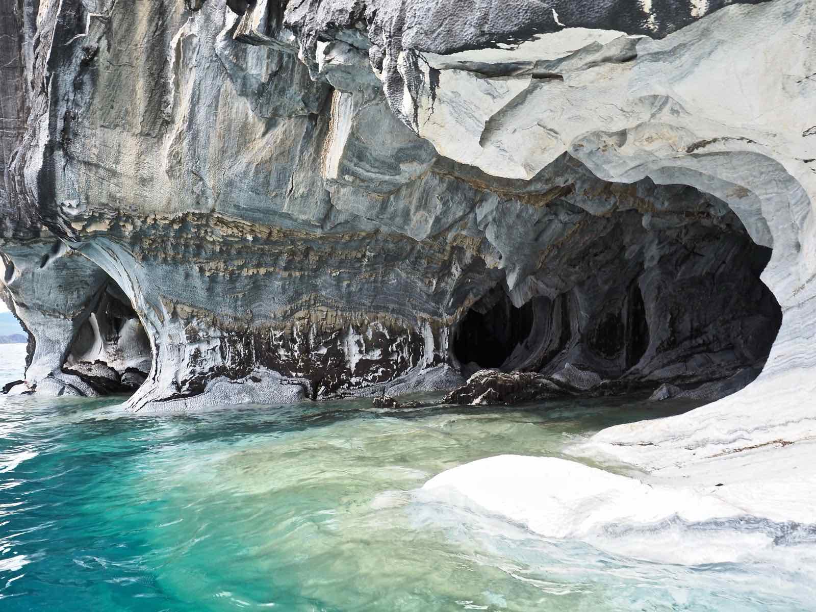 Fluted marble columns rising from the blue water at the edge of the Marble Caves