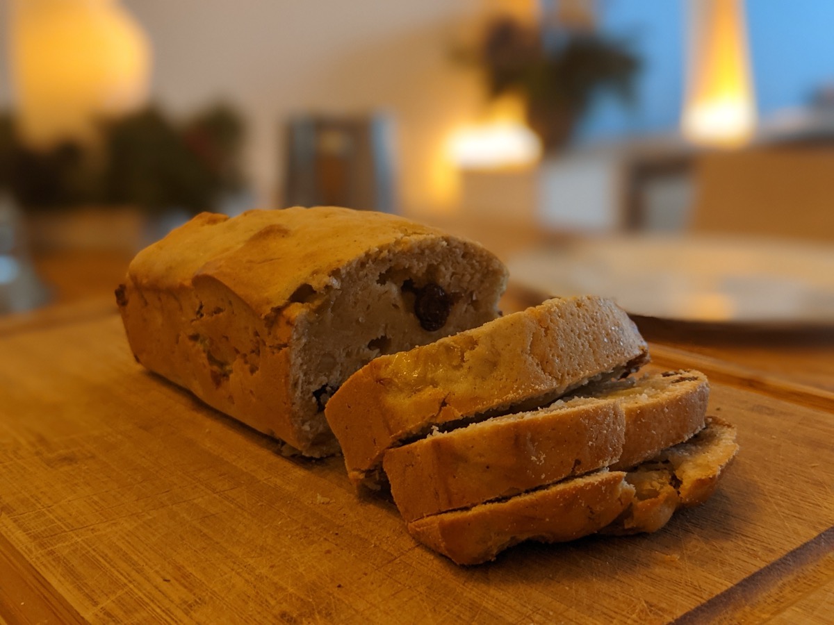 A loaf of banana nut bread, sliced, showing a moist crumb studded with walnuts