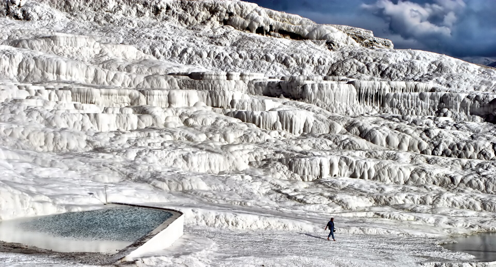 The hot spring pools of Pamukkale with visitors wading in the shallow warm turquoise water