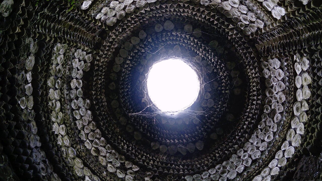 Looking straight up the shell-lined dome of the Shell Grotto toward a bright circular skylight