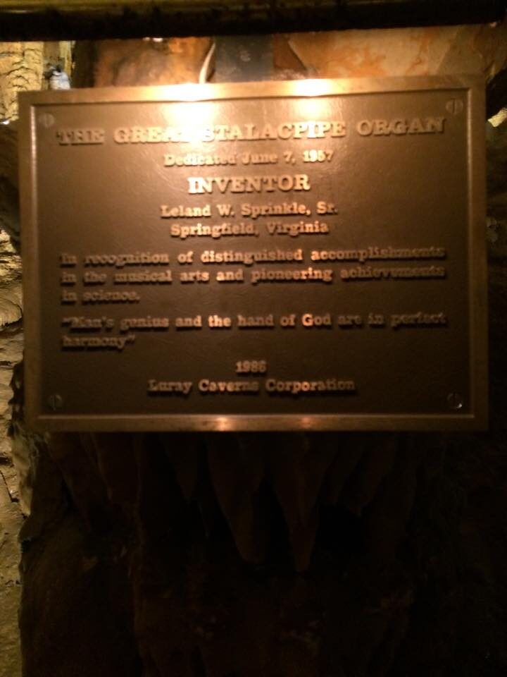 A bronze plaque in the cave reading 'The Great Stalacpipe Organ, Dedicated June 7, 1957, Inventor Leland W. Sprinkle, Sr., Springfield, Virginia'