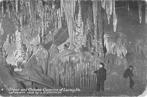 A 1906 black-and-white postcard captioned 'Organ and Chimes - Caverns of Luray, Va.', showing two men in hats among cave formations, one tapping a curtain of thin stalactites with a stick
