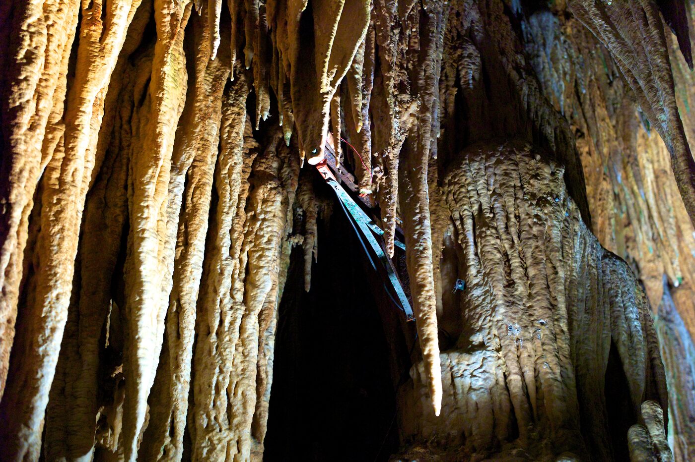 A striker unit mounted on a long metal bracket high among huge draperies and stalactites in Luray Caverns