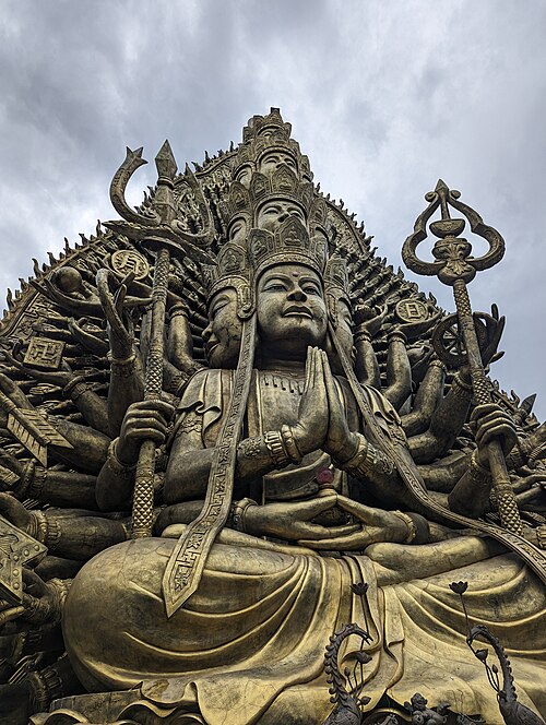 A large golden multi-armed Bodhisattva statue at Suoi Tien