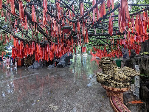 Hundreds of red prayer ribbons tied up near a golden dragon at Suoi Tien