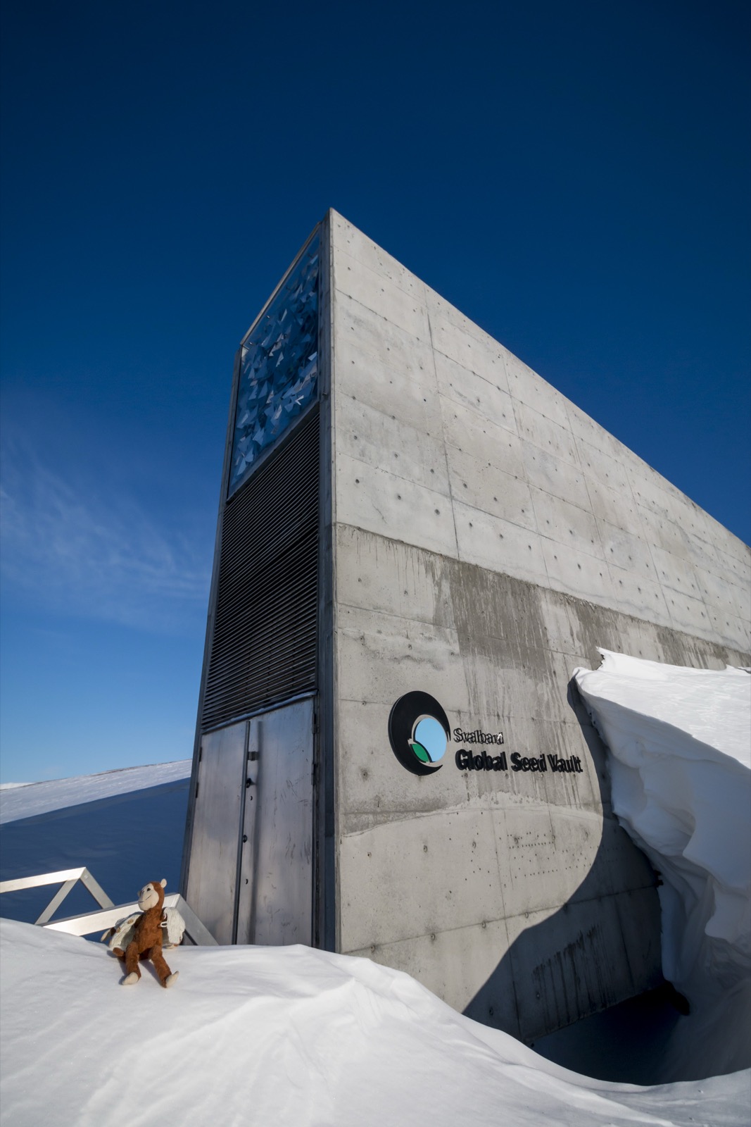 The illuminated top of the seed vault entrance glowing turquoise and white against a dim Arctic sky