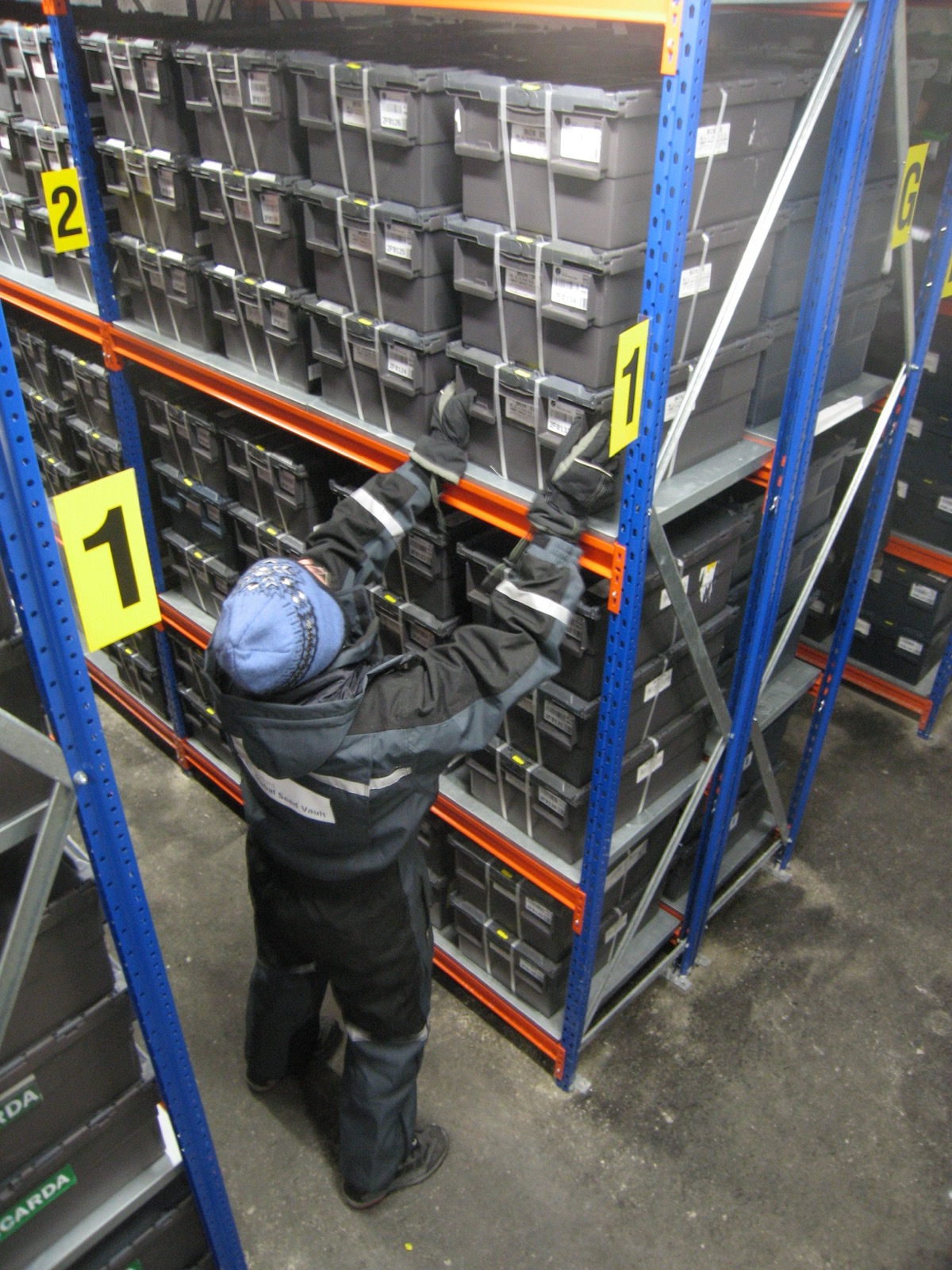 Shelves of labelled black and grey storage boxes filled with sealed seed packets inside the frozen vault