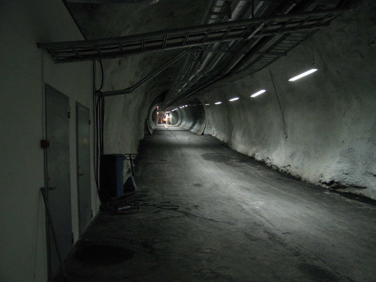 The long concrete-and-rock entrance tunnel leading into the seed vault, lit by a line of ceiling lights